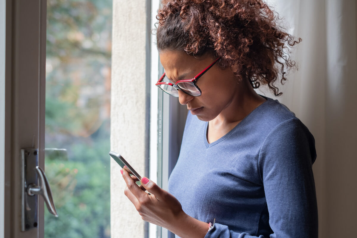 A woman looking at her phone with concern, stalking charges